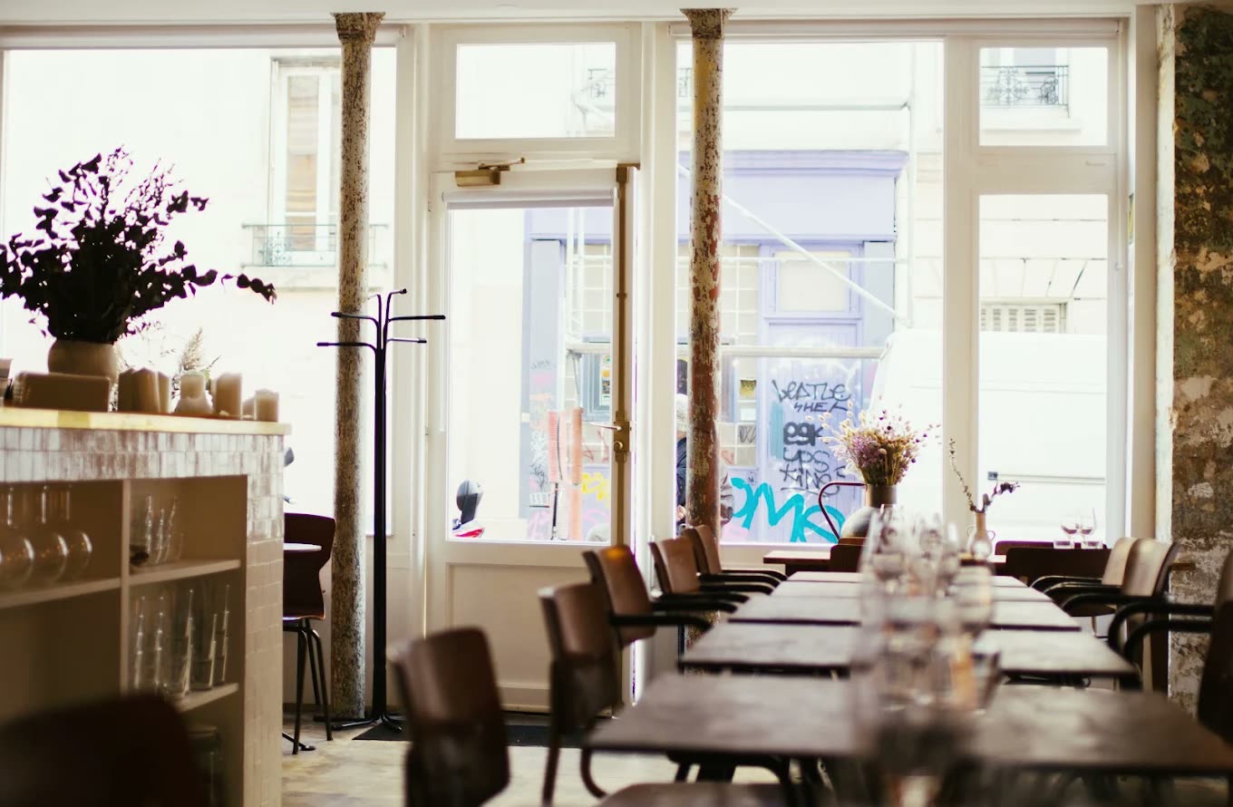 The dining room at Early June, laid tables and iron columns in bright daylight